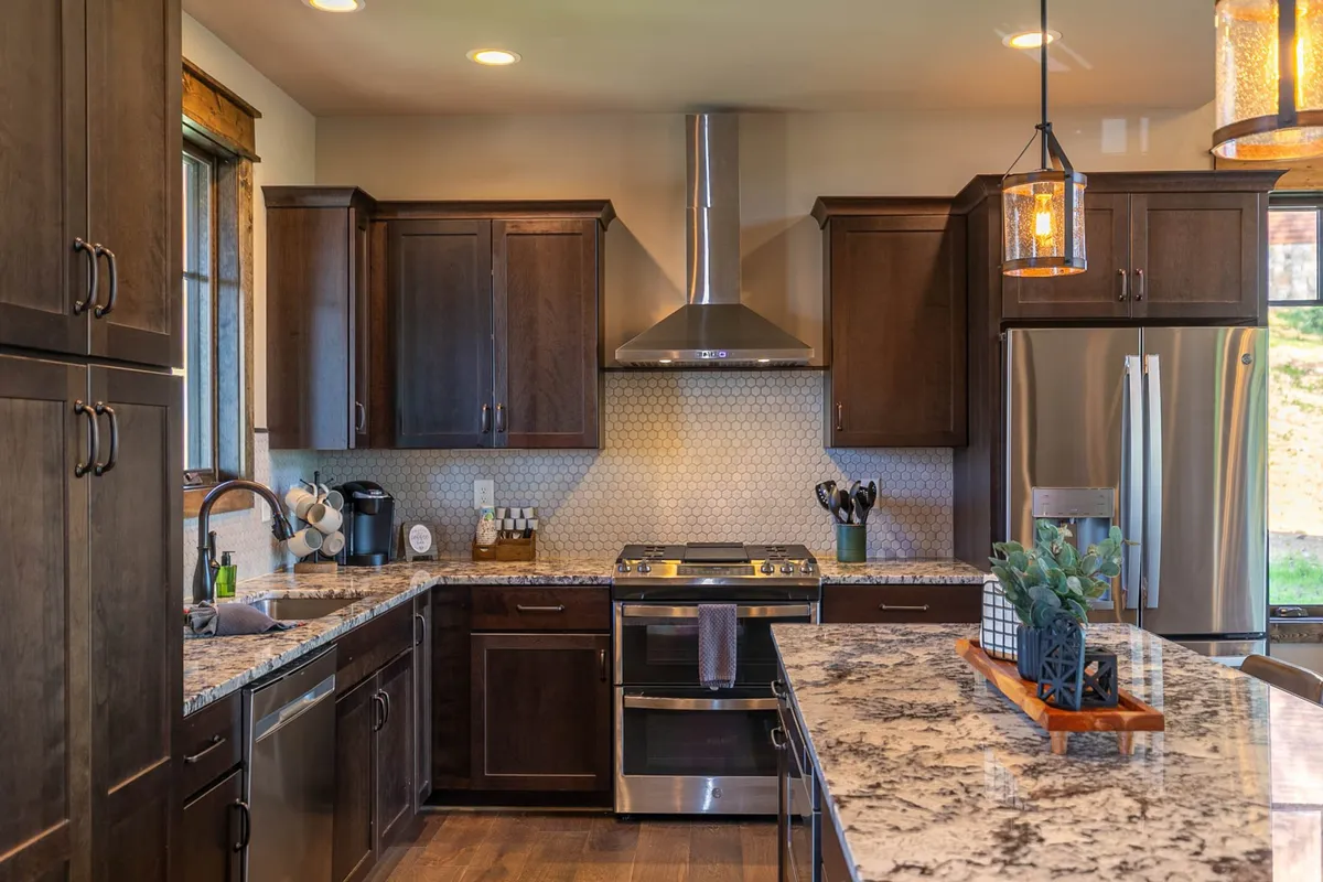 The scene centers on a chef-ready kitchen with stainless steel appliances, a granite countertop island, unique light fixtures, and a window letting in natural light. The design is both modern and inviting, ideal for family gatherings and culinary creativity.